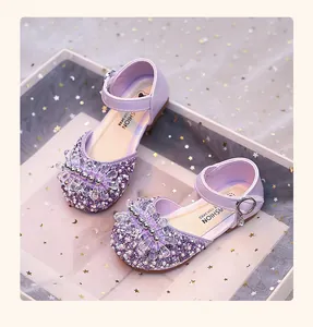 Gros plan de chaussures de princesse en cristal violet pour filles avec strass brillants.