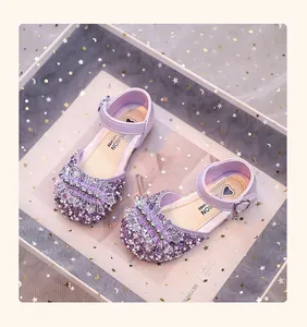 Gros plan sur les détails de fleurs en strass et perles des chaussures de princesse violettes.