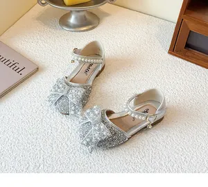 Detailansicht glitzernder silberner Mädchen-Prinzessinnenschuhe mit Perlenbogen und Riemchen.