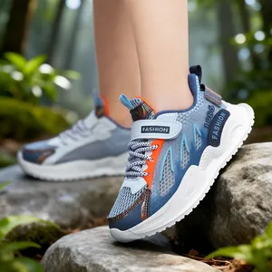 Zapatillas de deporte de malla transpirable azul y gris para niños sobre rocas al aire libre