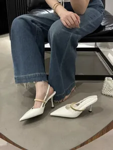 Close-up of elegant white pointed-toe high heels with a metallic gold buckle strap