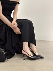 Elegant side view of black pointed-toe slingback heels with gold strap worn by a model