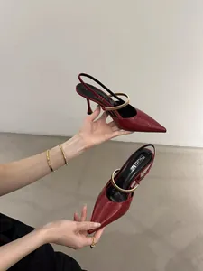 Close-up of red pointed-toe slingback heels with gold metallic strap detail