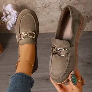 Nahaufnahme olivfarbener Wildleder-Loafer mit goldener Kette und Plateausohle.