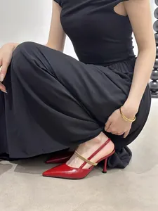 Detail view of elegant red pointed-toe slingback heels with a gold strap on model