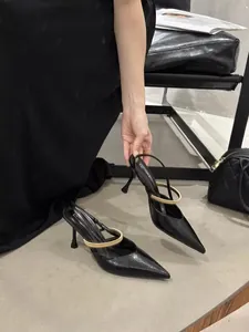 Close-up detail of elegant black pointed-toe heels with gold metallic strap decoration