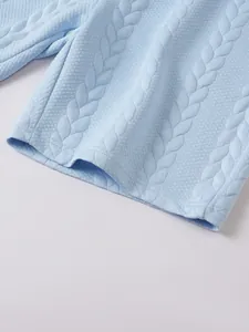 Close-up detail of light blue shorts showing intricate jacquard cable knit texture