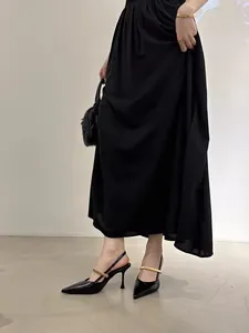 Close-up detail of black pointed-toe slingback heels featuring elegant gold metal strap