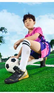 Vue détaillée des chaussures de football TF noires et dorées pour enfants sur gazon synthétique