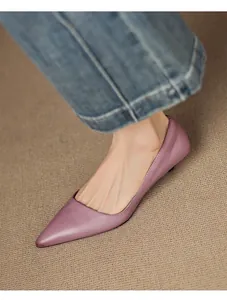 Close-up of elegant lavender pointed-toe flats worn with denim jeans.