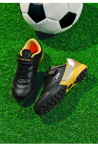 Gros plan de chaussures de foot TF enfant avec crampons sur gazon
