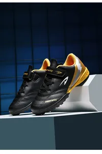Vue latérale dynamique des chaussures de football TF noires et jaunes pour enfants