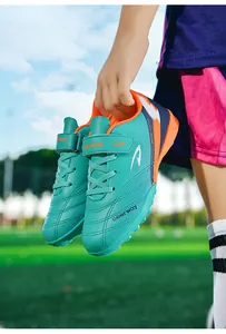 Gros plan de chaussures de football pour enfants turquoise avec détails orange.