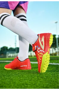 Primo piano di scarpe da calcio TF rosse per bambini su erba sintetica