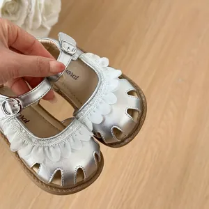 Gros plan de sandales de marche argentées pour filles avec volants en dentelle