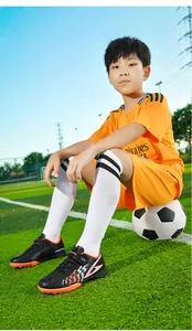 Primo piano di scarpe da calcio TF per bambini indossate sul campo