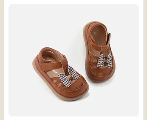 Detailansicht der braunen Kleinkindsandalen für Mädchen mit Karoschleifen und Lochmuster.