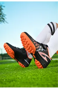 Dettaglio delle scarpe da calcio per bambini con suole arancioni e chiusura a strappo