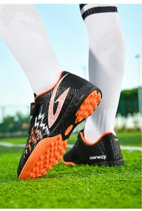 Dettaglio di scarpe da calcio per bambini con tacchetti TF su campo di erba sintetica