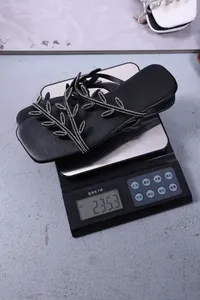 Black square toe flat sandals with leaf rhinestones weighed on scale at 235.3g