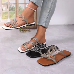 Detailed view of women's leaf-pattern crystal flat sandals in white, black and brown