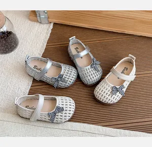 Nahaufnahme von gewebten Kinder-Mary-Janes in Silber und Beige mit Karoschleifen.