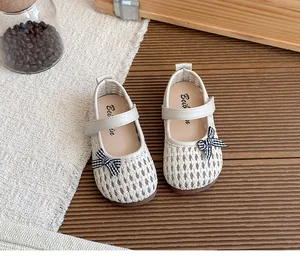 Detailansicht von cremefarbenen geflochtenen Kinder-Mary-Janes mit Karoschleifen