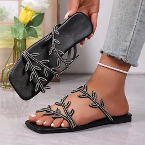 Detail of black flat sandals with rhinestone leaf straps and square toe design