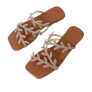 Elegant brown flat sandals with rhinestone leaf straps and a modern square toe.