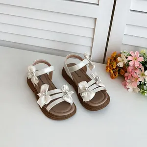 Detailansicht weißer Kindersandalen mit Seidenbandschleifen und Perlenapplikationen