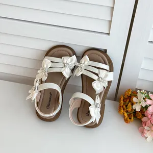 Nahaufnahme von weißen Mädchen-Sommersandalen mit dekorativen Seidenschleifen und Perlen