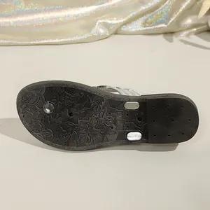Close-up of the non-slip patterned black sole of a fashionable women's silver flip-flop.