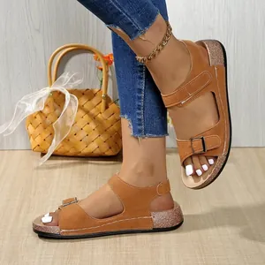 Vista dettagliata dei sandali piatti da donna in camoscio marrone con velcro.
