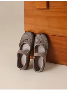 Primer plano de zapatos planos de cuero marrón perforado con flores y cierre de velcro