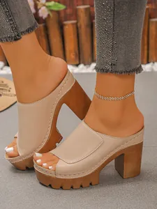 Detail view of beige chunky platform peep-toe mule sandals worn with an anklet