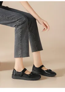 Detalle de los zapatos planos de cuero negro transpirable con cierre de velcro en una modelo.