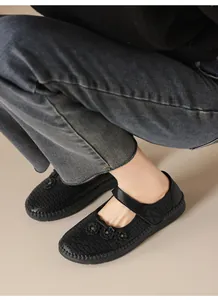 Primer plano de manoletinas de cuero negro con detalle de flores caladas en modelo.