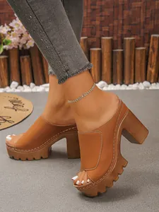 Detailed view of women wearing brown platform peep toe mules with chunky high heels