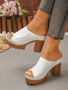 Detailed side view of white platform chunky heel peep-toe mules with textured brown soles