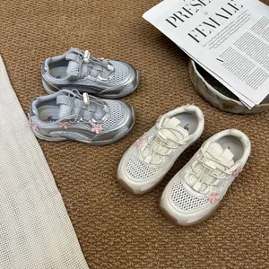 Close-up detail of girls' breathable mesh sneakers in silver and cream with floral accents.