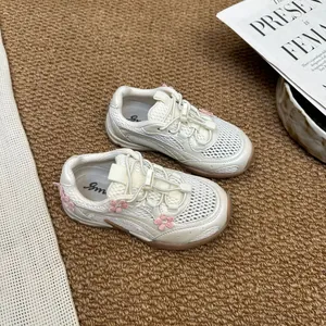 Detailed view of white mesh girls' sneakers with cute pink flower accents and toggle laces.