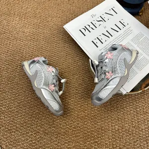 Detailed macro view of silver breathable mesh sneakers for girls with pink floral appliqués
