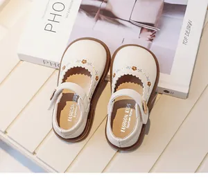Detailed view of white toddler Mary Jane shoes with floral embroidery and scalloped trim.
