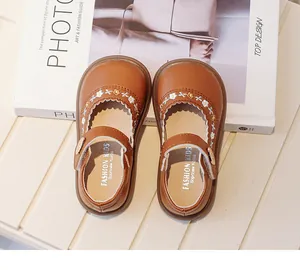Detailed view of toddler brown leather shoes with white floral embroidery details