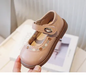 Close-up of pink toddler girl's leather shoes with floral embroidery and soft soles.