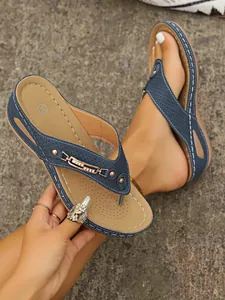 Primer plano de chanclas azules con cadena y costuras en contraste.