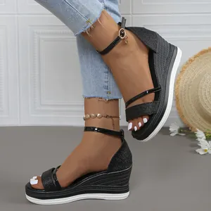 Primer plano de sandalias de cuña con plataforma negras con correa al tobillo y brillo