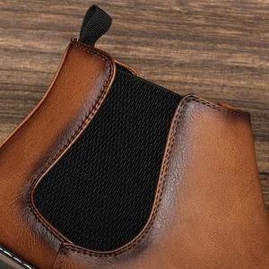 Detailed close-up of burnished brown leather and elastic panel on a men's Chelsea boot