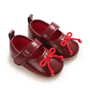 Detail von weinroten Baby-Lacklederschuhen für Mädchen mit roter Seilschleife.