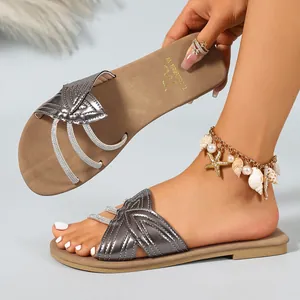 Detail of metallic silver flat sandals with stylish criss-cross straps on a model.